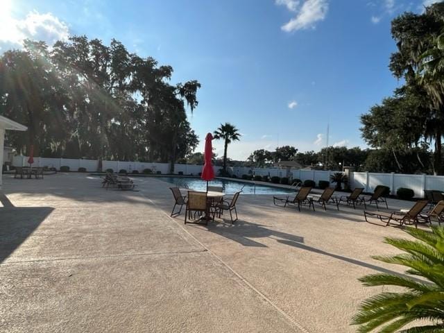 surrounding community featuring a patio area, a swimming pool, and fence