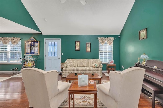 living room with vaulted ceiling, wood-type flooring, and a healthy amount of sunlight