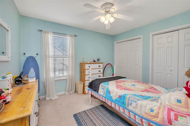 bedroom featuring two closets, light colored carpet, and ceiling fan