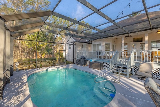 view of pool with a patio area, a deck, glass enclosure, and french doors