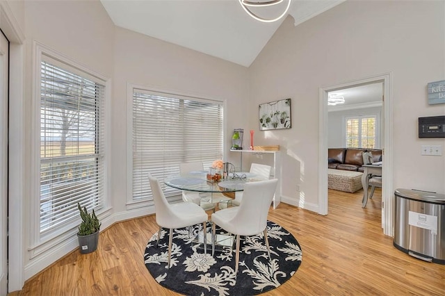 dining room featuring high vaulted ceiling and light hardwood / wood-style flooring