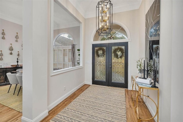 entrance foyer featuring an inviting chandelier, hardwood / wood-style flooring, crown molding, and french doors