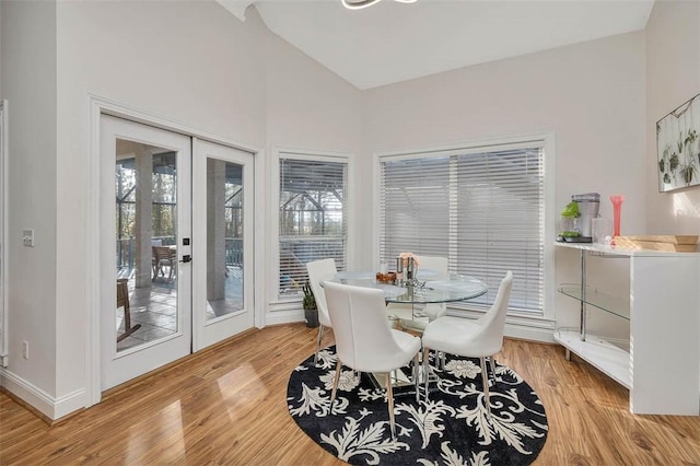 dining room with french doors, vaulted ceiling, and light wood-type flooring