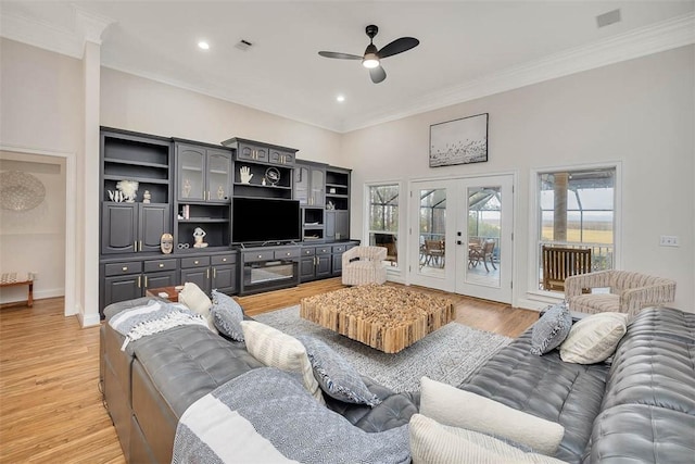 living room featuring crown molding, french doors, ceiling fan, and light wood-type flooring