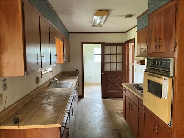 2608 Winchester Dr, Waycross, GA 31501 - kitchen with oven, concrete flooring, brown cabinets, ornamental molding, and stainless steel stovetop