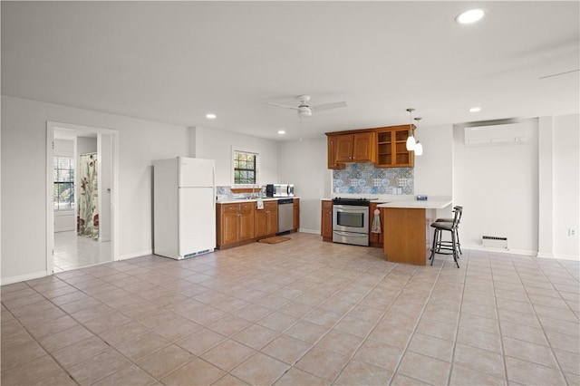 kitchen featuring pendant lighting, appliances with stainless steel finishes, a wall mounted AC, a kitchen bar, and kitchen peninsula