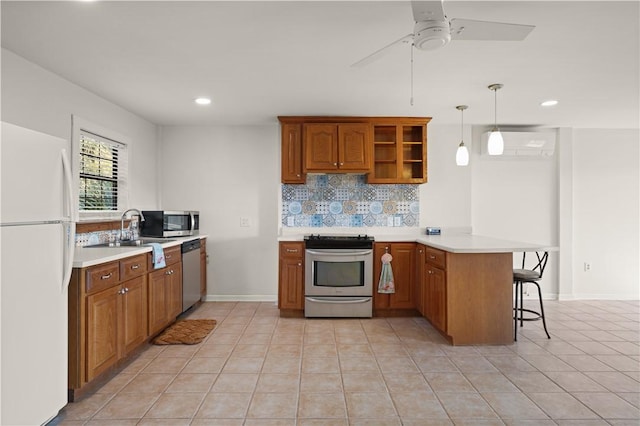 kitchen featuring pendant lighting, a kitchen breakfast bar, a wall mounted AC, kitchen peninsula, and stainless steel appliances