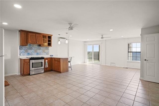 kitchen featuring backsplash, stainless steel range oven, light tile patterned floors, and hanging light fixtures