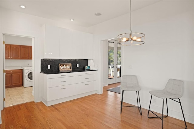 kitchen with white cabinets, light wood-type flooring, and washer / dryer