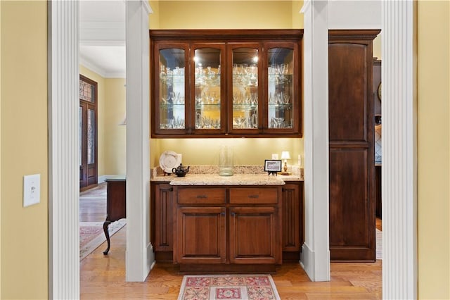 bar with ornamental molding and light wood-type flooring