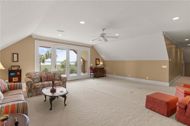 living room with a textured ceiling, lofted ceiling, light carpet, visible vents, and baseboards