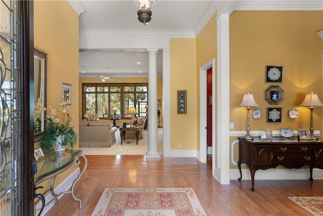 foyer entrance with crown molding, decorative columns, a ceiling fan, wood finished floors, and baseboards