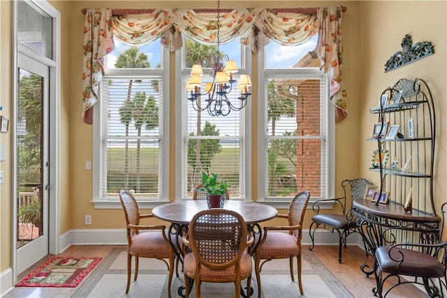 dining space featuring light wood finished floors, a healthy amount of sunlight, and an inviting chandelier