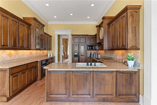 kitchen featuring glass insert cabinets, a peninsula, light stone countertops, black appliances, and a sink