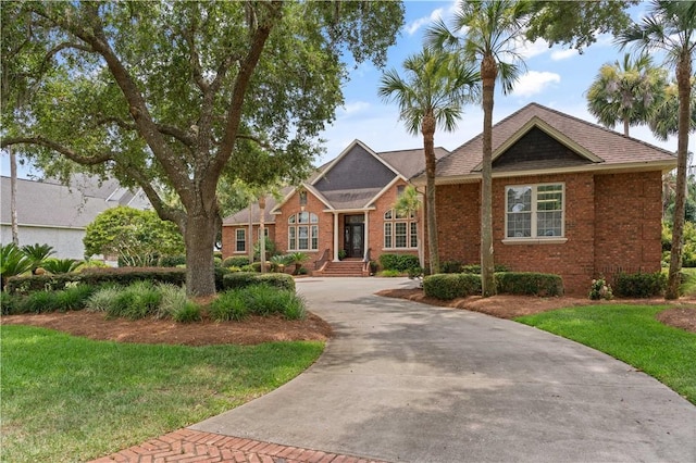 view of front of house with a front yard, concrete driveway, and brick siding