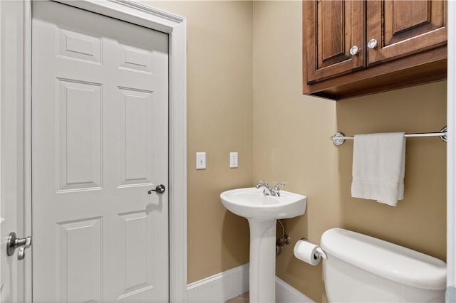 half bathroom with baseboards and toilet