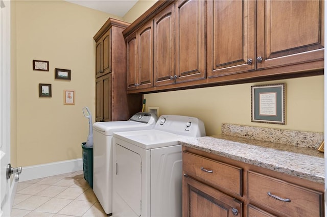 clothes washing area featuring light tile patterned floors, cabinet space, baseboards, and separate washer and dryer