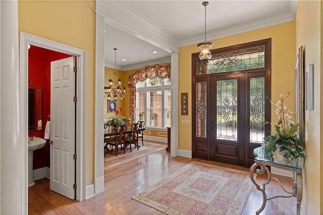 entrance foyer with light wood-style floors, a chandelier, ornamental molding, and baseboards