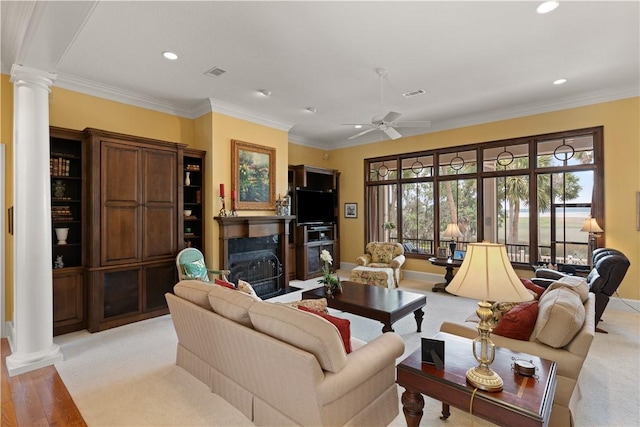 living room featuring crown molding, visible vents, a fireplace, and ornate columns