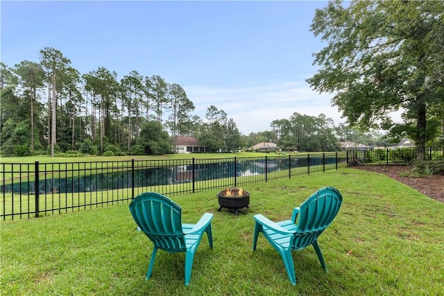 view of yard with a water view, fence, and a fire pit