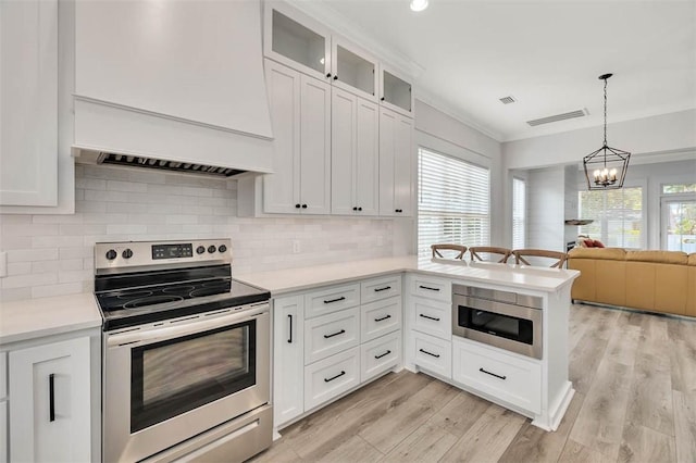 kitchen with white cabinets, pendant lighting, stainless steel appliances, and plenty of natural light