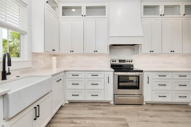 kitchen featuring electric range, white cabinetry, and sink