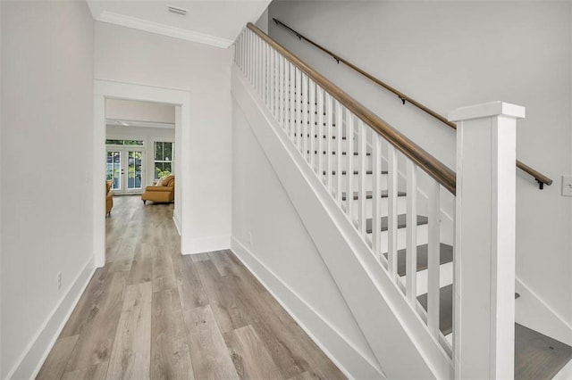 staircase featuring wood-type flooring, crown molding, and french doors