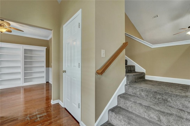 staircase featuring crown molding, a ceiling fan, and baseboards