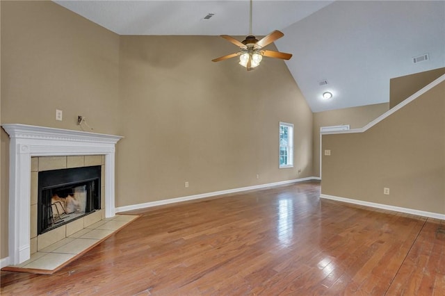 unfurnished living room featuring visible vents, a tiled fireplace, ceiling fan, wood finished floors, and baseboards