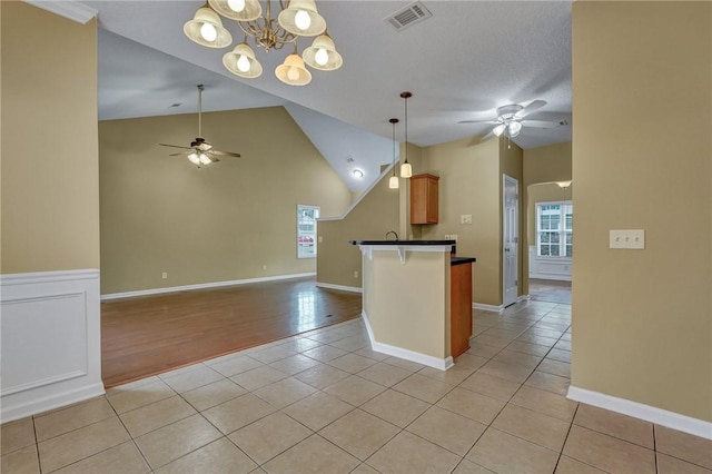 kitchen featuring light tile patterned floors, dark countertops, visible vents, open floor plan, and plenty of natural light