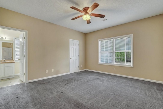 unfurnished room with light carpet, baseboards, visible vents, a ceiling fan, and a textured ceiling