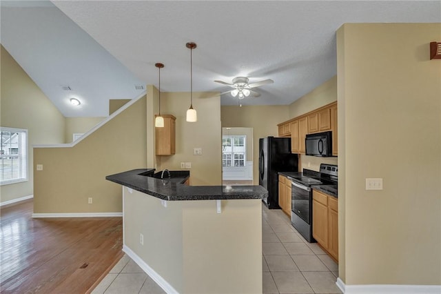 kitchen featuring a breakfast bar, dark countertops, hanging light fixtures, a peninsula, and black appliances