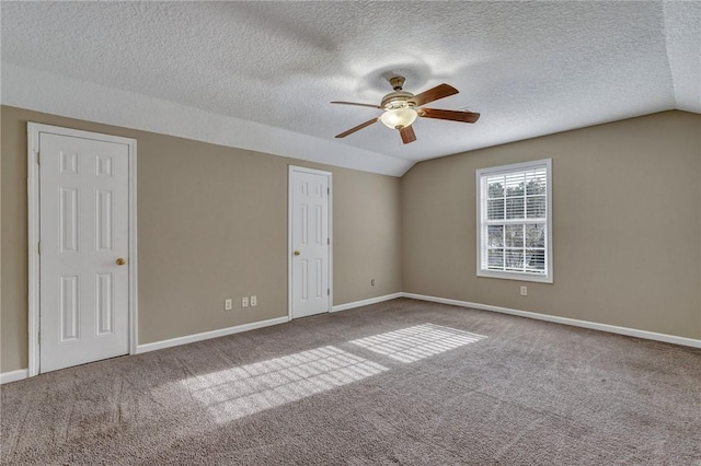 carpeted empty room with lofted ceiling, ceiling fan, and baseboards