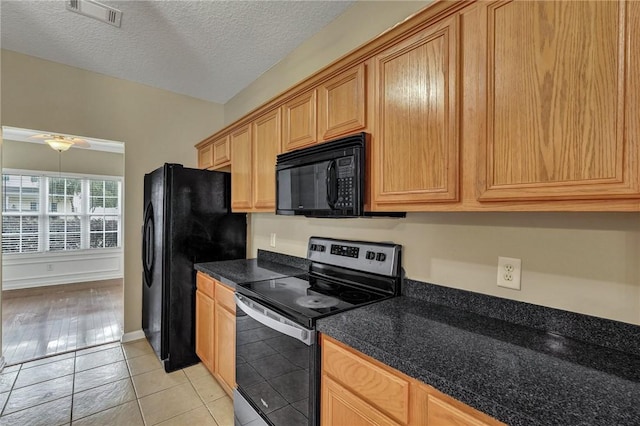 kitchen featuring light tile patterned floors, a textured ceiling, visible vents, black appliances, and dark countertops