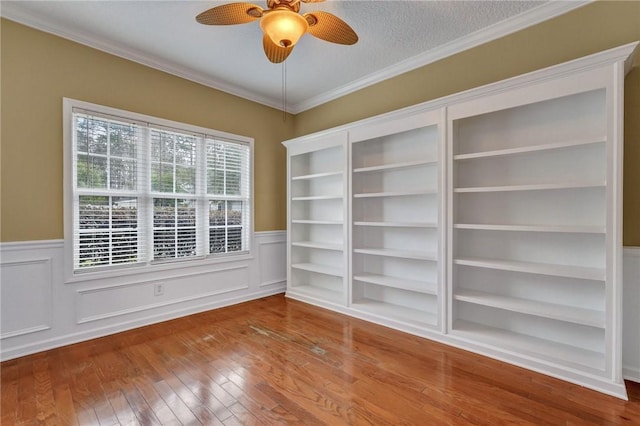 spare room with ornamental molding, wainscoting, and hardwood / wood-style floors