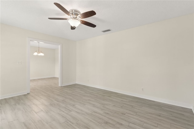 unfurnished room with visible vents, light wood-type flooring, baseboards, a textured ceiling, and ceiling fan with notable chandelier