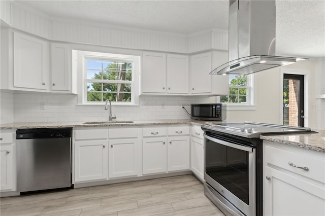 kitchen with white cabinets, island range hood, a sink, a textured ceiling, and appliances with stainless steel finishes