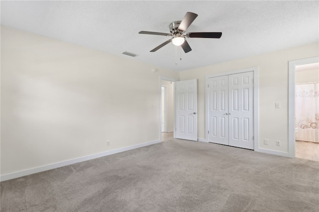 unfurnished bedroom featuring a textured ceiling, a closet, carpet, baseboards, and visible vents