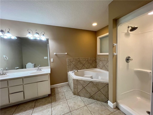 bathroom with tiled tub, tile patterned flooring, vanity, and a textured ceiling