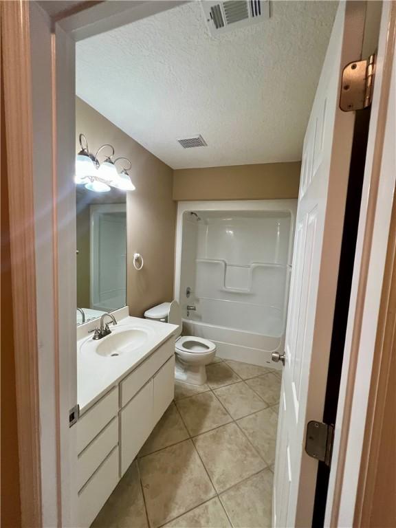 full bathroom with tile patterned flooring, vanity, toilet, and a textured ceiling