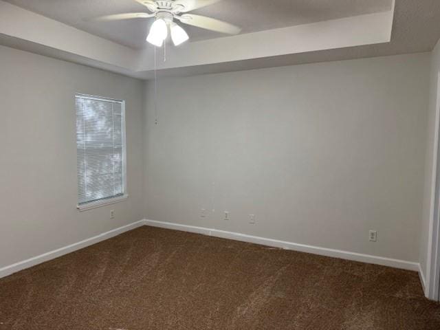 carpeted spare room featuring ceiling fan and a raised ceiling