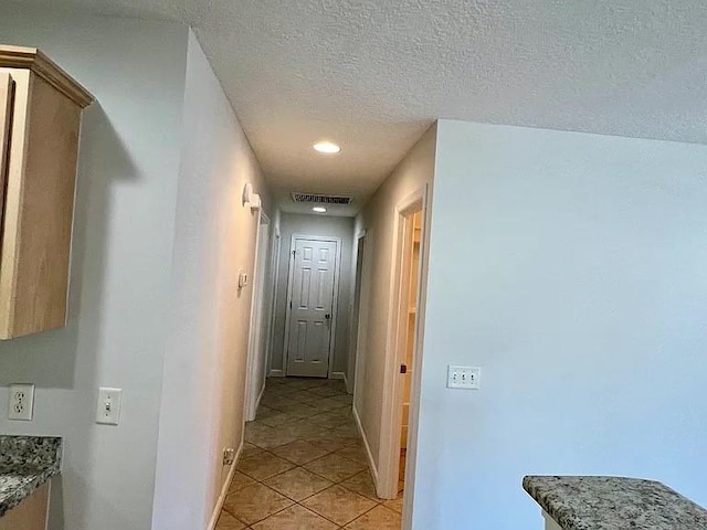 corridor with light tile patterned floors and a textured ceiling