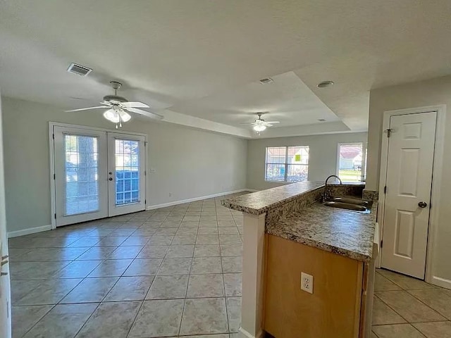 kitchen with a tray ceiling, sink, light tile patterned floors, and french doors