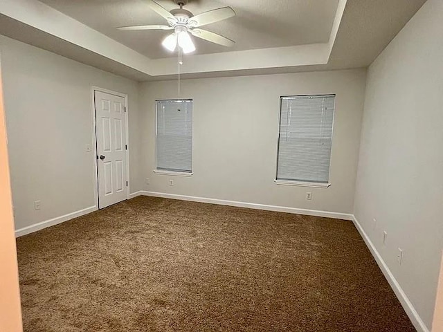 empty room featuring carpet, ceiling fan, and a tray ceiling