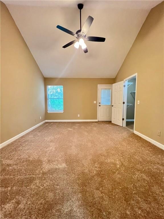 unfurnished bedroom with carpet flooring, a spacious closet, ceiling fan, and high vaulted ceiling