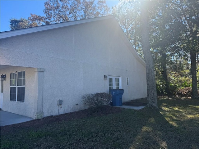 view of property exterior featuring french doors and a lawn