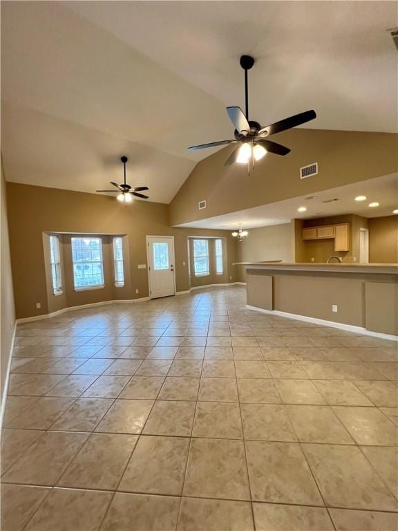 unfurnished living room with ceiling fan with notable chandelier, light tile patterned flooring, and vaulted ceiling