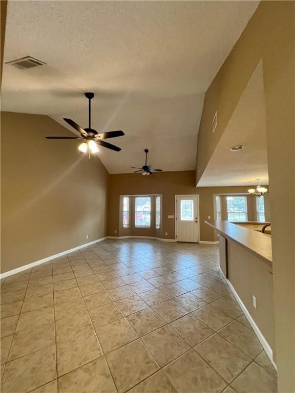 unfurnished living room with light tile patterned floors, a wealth of natural light, lofted ceiling, and ceiling fan