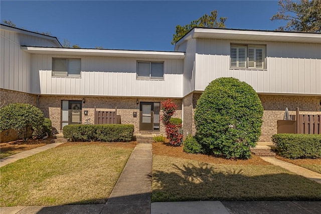 multi unit property featuring brick siding and a front yard