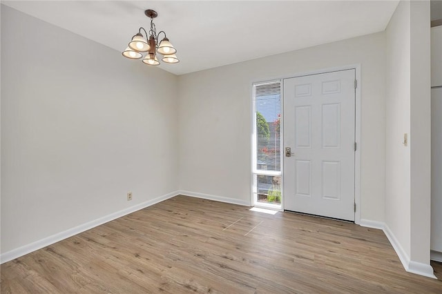 entrance foyer featuring light wood-type flooring, baseboards, and a chandelier